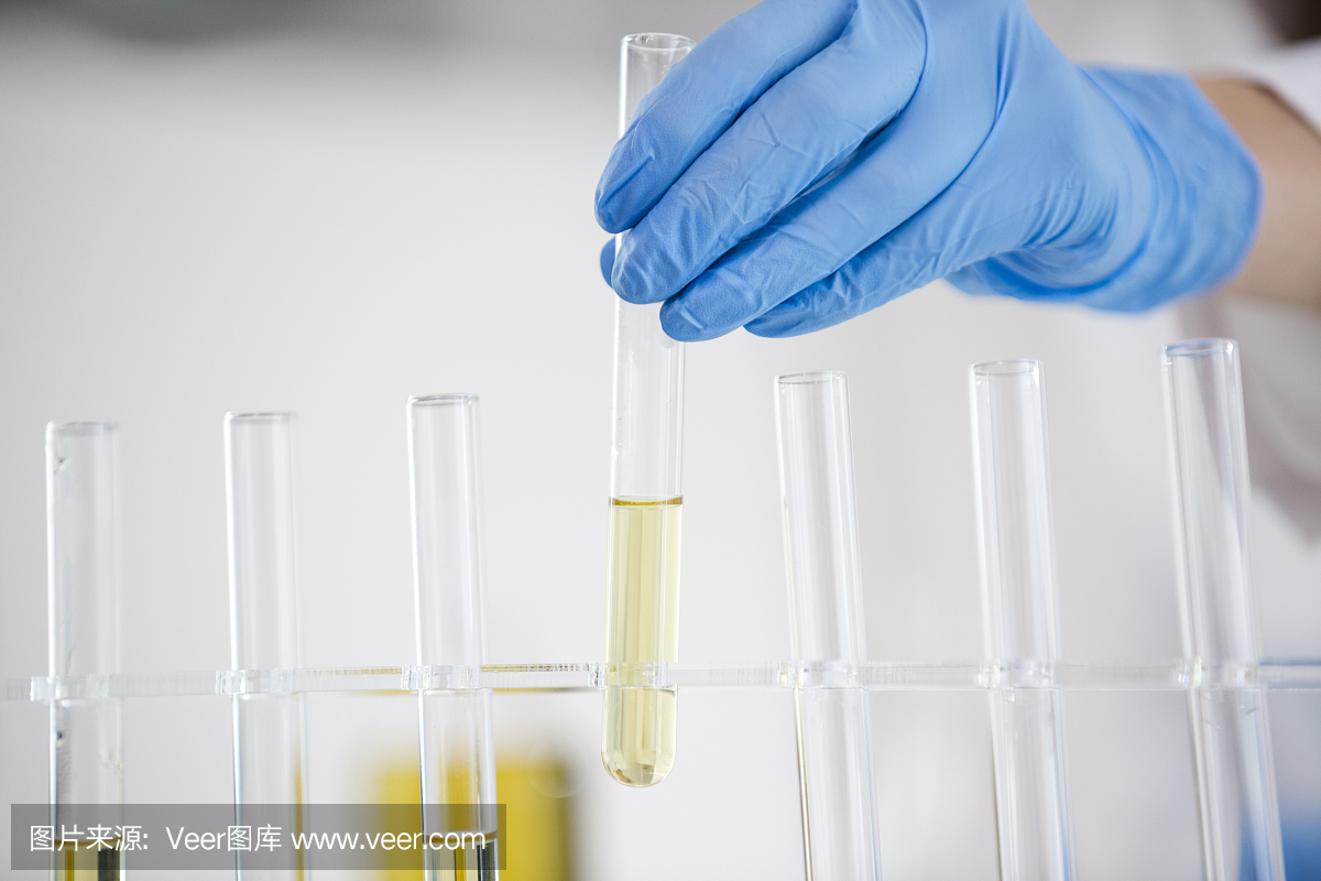 一个女性科学家在实验室工作与从大麻植物中提取的CBD油的特写。用玻璃管滴定CBD油。